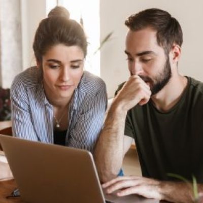A couple looks intently at their laptop.