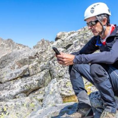 A man on his phone on top of a mountain ridge.