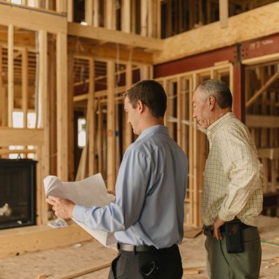 2 Men looking at blueprints in new home that is still under construction.