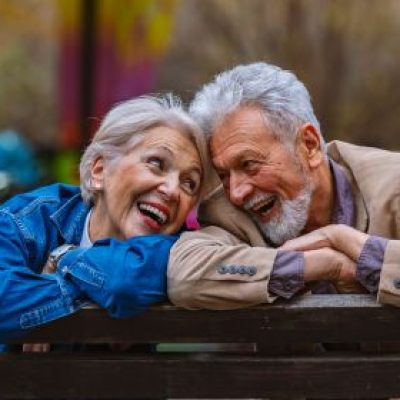 A happy elderly couple leaning on a railing.