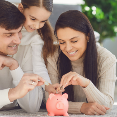 A young family puts quarters into a pink piggy bank.
