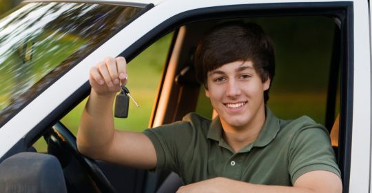 Teenage boys holds the keys to his first car.