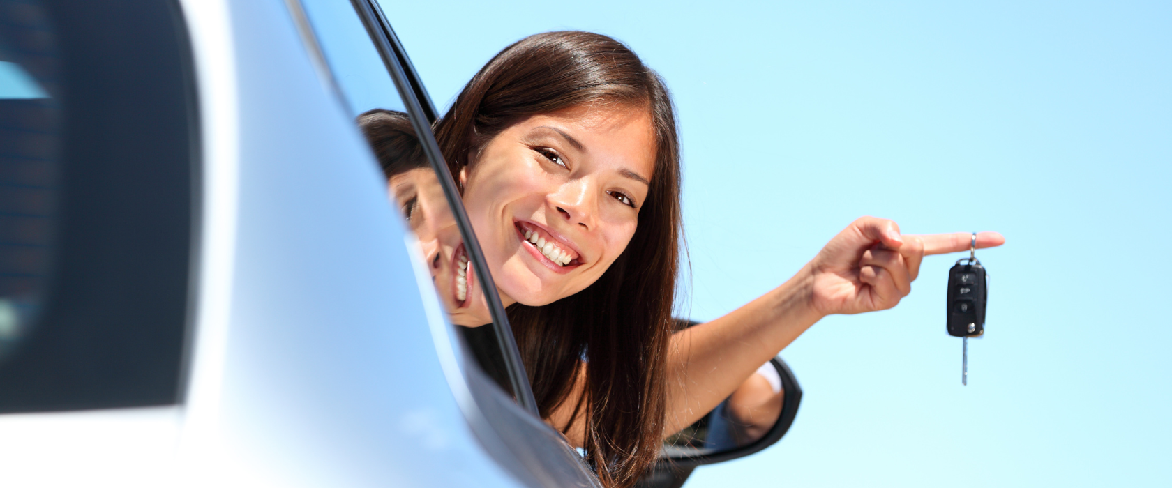 a teenaged girl in her new car, sticking her head out the window holding the keys with one finger.