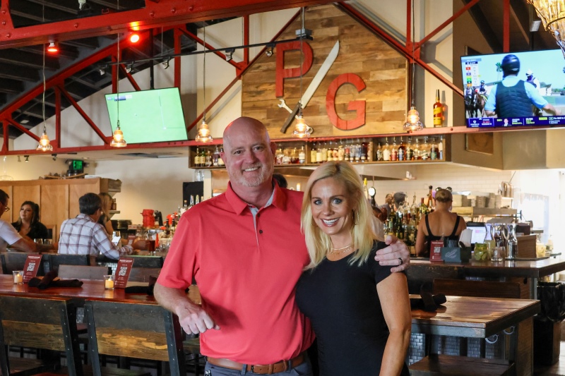 Parker Garage owners standing inside the restaurant in front of the bar smiling at the camera