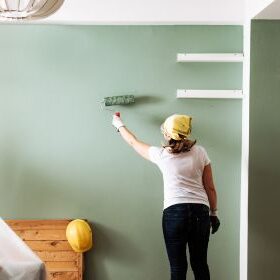 A woman paints a wall green in her house.