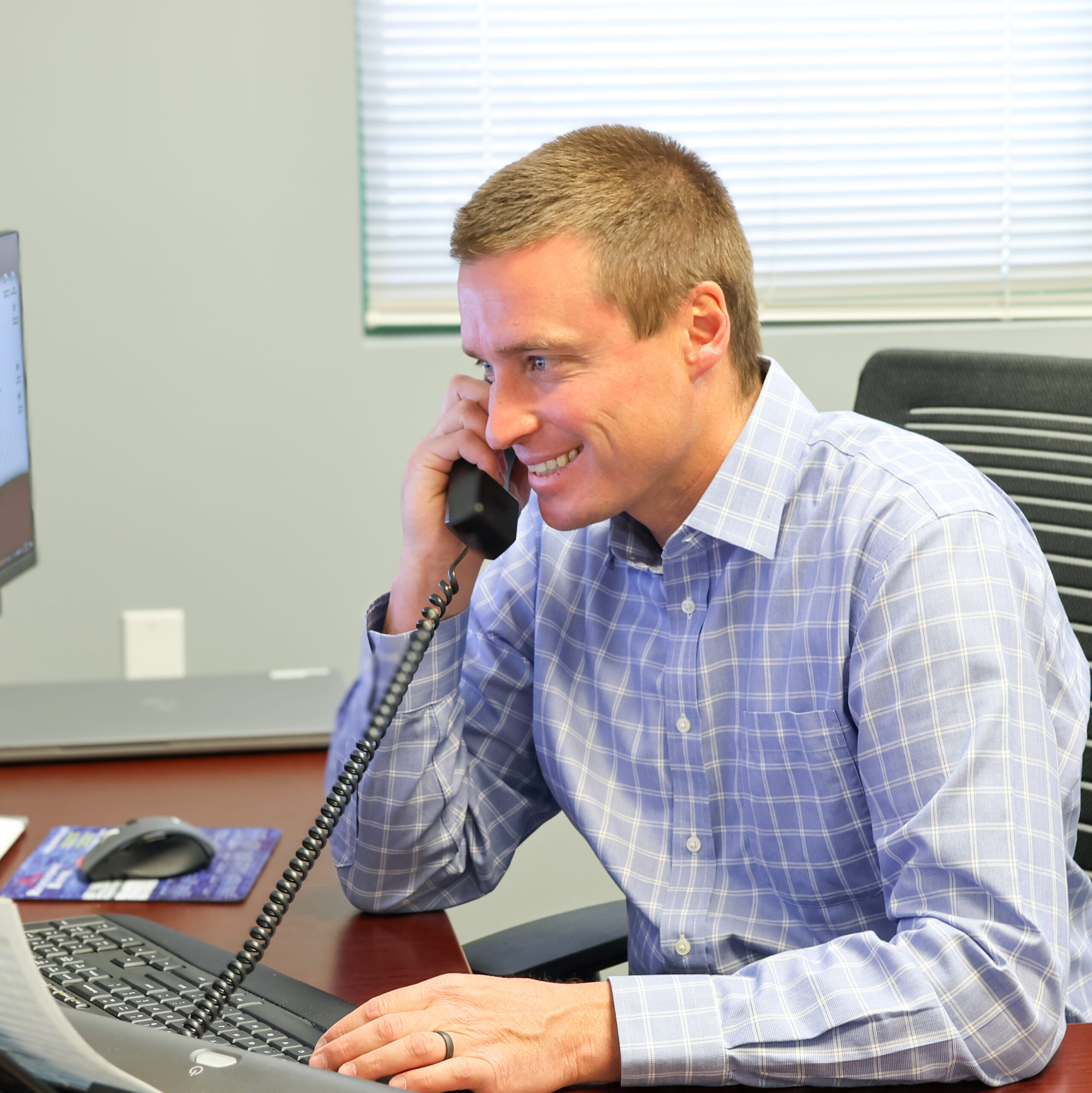 Dillon Joslyn, on the phone at his desk helping a client with their new business questions.