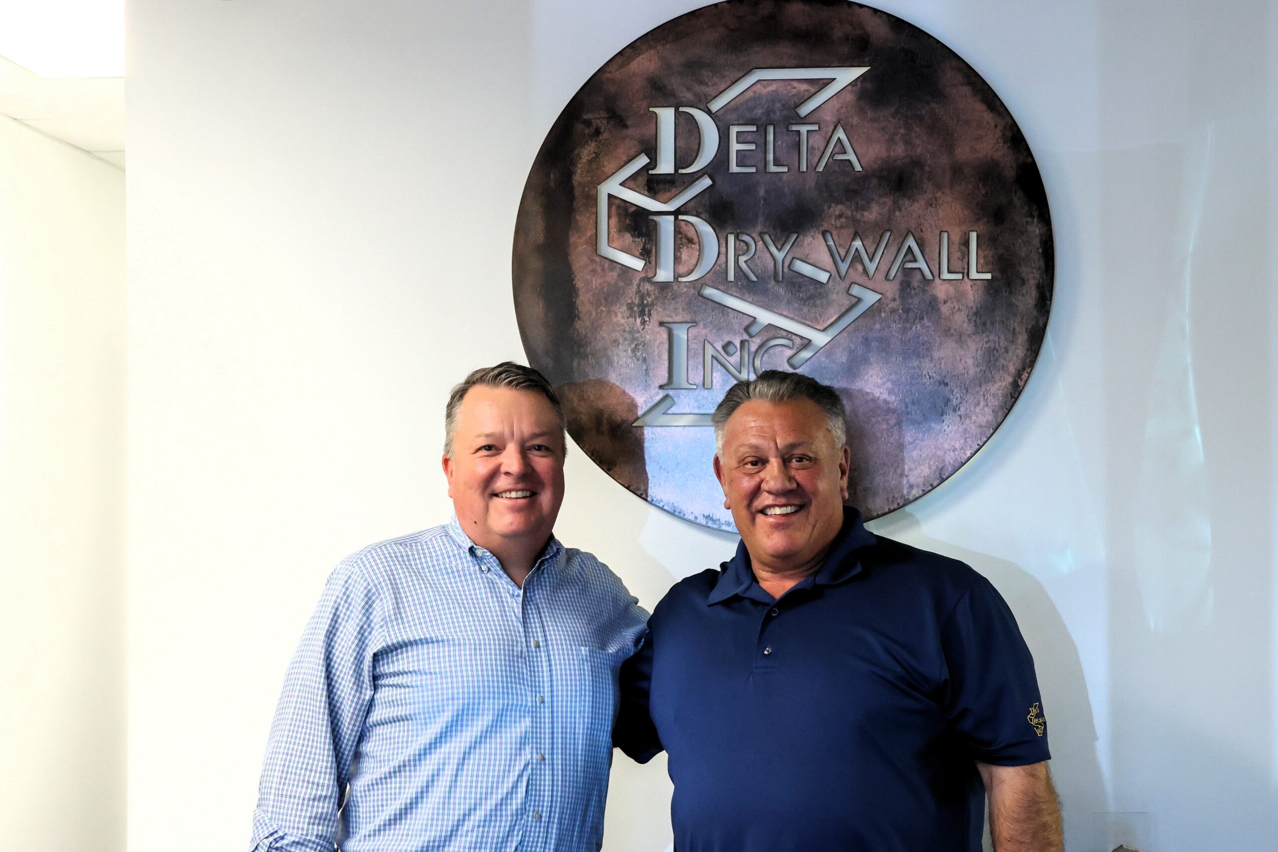 Heath and Rusty in front of the Delta Drywall sign