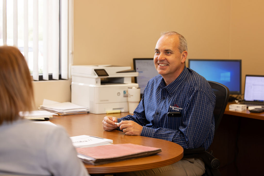 Josh Dearmore, Loan Officer helping a client in his office with a personal loan.